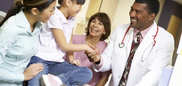 Stock photo of clinicians with mother and child in a medical office.