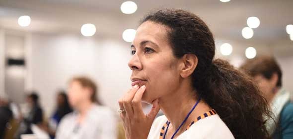  A woman looking engaged while a presenter discusses leadership in healthcare organizations. 