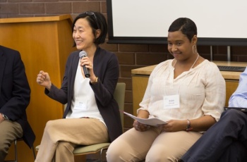Photo of four people talking to an audience with one person holding a microphone.