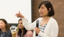 Photo of Dr. Sunita Mutha speaking with a microphone at a large meeting.