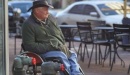 Photo of older man with a cowboy hat in a wheelchair at a sidewalk cafe