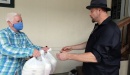 Photo of person handing bags of food to another person.